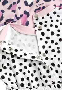 Due pezzi di abbigliamento: uno con una stampa leopardata rosa e viola scuro, l'altro bianco con pois neri. Presentano bottoni a pressione e un tessuto morbido.