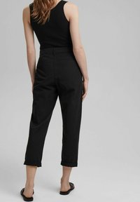 Pantalon noir à coupe décontractée, ourlets retroussés et deux poches arrière. Fabriqué en tissu doux, avec une texture lisse et un design épuré.