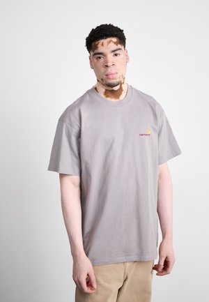 Gray cotton t-shirt with short sleeves, round neck, featuring a small red and yellow logo on the chest. Smooth texture, relaxed fit.