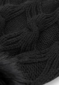 Czarna dzianina o fakturze warkocza, z miękkimi włóknami i lekko puszystym wyglądem, podkreślająca ciepło i przytulność.