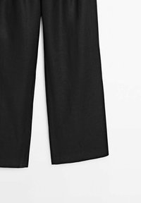 Pantalon noir à jambes larges montré de la moitié de la cuisse vers le bas sur fond blanc, avec un ourlet ample et droit.