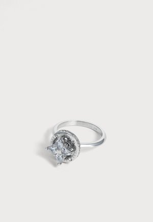 Bague en argent avec quatre pierres précieuses triangulaires transparentes disposées en grappe sur une base ronde avec de petits détails gravés.