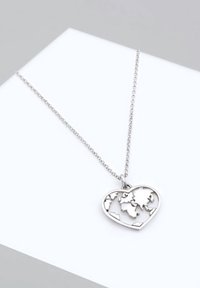 Collier en argent avec un pendentif en forme de cœur présentant un motif de carte du monde découpé, exposé sur une surface blanche.