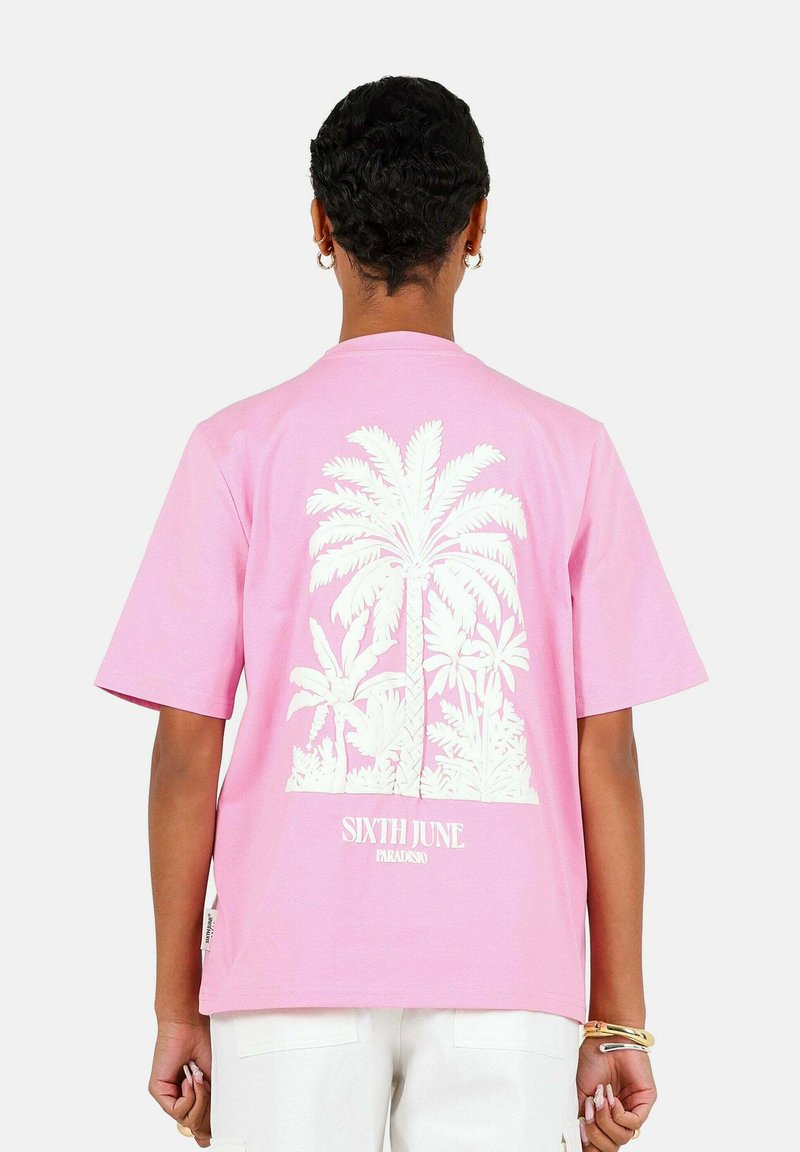 Roze t-shirt met korte mouwen, met een witte palmbomenafbeelding op de achterkant en de tekst "SIXTH JUNE PARADISE" nabij de zoom.