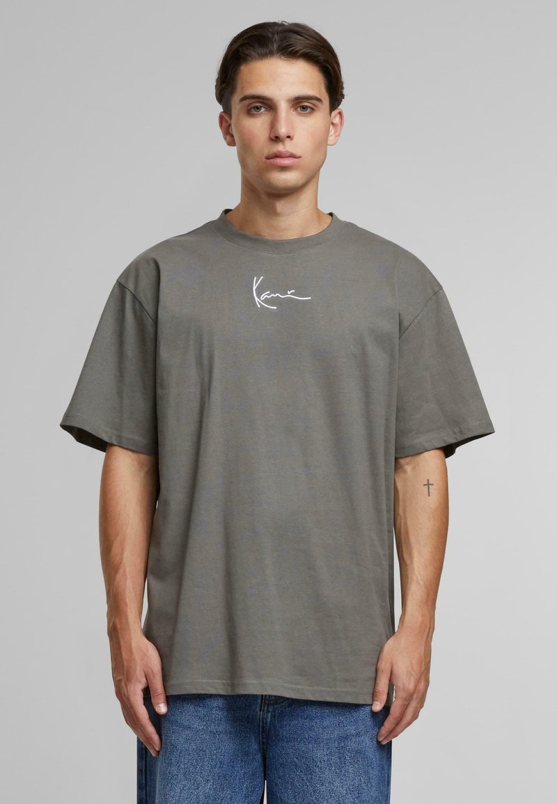 T-shirt en coton gris avec une coupe décontractée et des manches courtes. Présente un logo signature blanc sur la poitrine et un col rond.