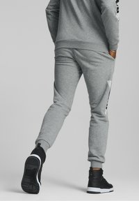Sweatshirt gris et pantalon de survêtement assorti en tissu doux, présentant un design minimaliste et des accents noirs. Des chaussures montantes noires sont incluses.