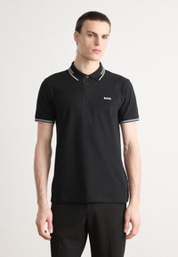 Čierna polo tričko vyrobené z bavlny, s klasickým golierom s bielymi pásikmi, gombíkovou légou a malým logom na hrudi.