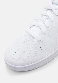 Baskets blanches en cuir avec un bout perforé, des lacets plats et un panneau latéral texturé. Semelle en caoutchouc arrondie avec détails cousus.