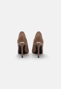 Hnedé kožené topánky na vysokom opätku s špicatou špičkou a elegantným dizajnom. Obsahujú čiernu podrážku a malý kovový akcent na opätku.