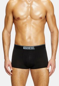 Μαύρα σλιπ μποξέρ από ελαστικό ύφασμα με γκρίζα ελαστική ζώνη που φέρει το λογότυπο "DIESEL". Λείος υφασμάτινος χαρακτήρας, εφαρμοστή σιλουέτα.