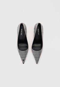 Crne pumpe s istaknutim vrhom i teksturiranom površinom prekrivene srebrnim cirkonima, s glatkom crnom unutrašnjošću i brendiranjem na ulošku.