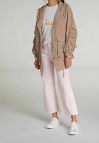 Beżowa, lekka kurtka z kapturem, dwa przednie kieszenie, w połączeniu z różowymi, krótkimi spodniami i białymi trampkami. Casualowy strój o luźnym kroju.