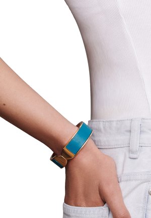 Turquoise leather bracelet with a gold metal accent, featuring a rectangular design and a smooth texture, worn on a wrist.