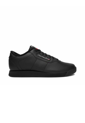 Černá nízká teniska Reebok se šňůrkami, hladkým koženým svrškem a logem na boku a jazyku, zobrazená z boku na bílém pozadí.