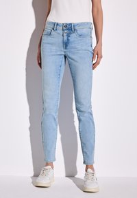 Jeans skinny in denim azzurro chiaro con vita media, dotati di zip e due tasche frontali, e una finitura effetto sbiadito.