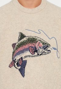 Beżowy sweter z kolorowym, dzianinowym wzorem ryby z różowymi, zielonymi i niebieskimi akcentami oraz grafiką wędki.