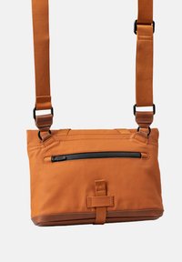 Orange Crossbody-Tasche aus strukturiertem Stoff, mit einem Reißverschlusstaschen an der Vorderseite und verstellbarem Tragegurt. Verfügt über einen glatten Lederboden und Akzente.