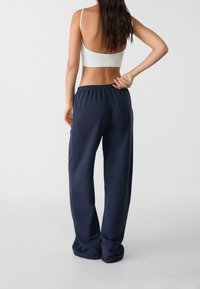 Námořnické modré tepláky mají elastický pas a uvolněný střih, jsou vyrobeny z měkkého materiálu, mají hladký povrch a minimální švy.