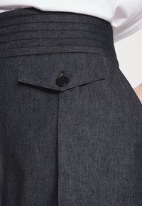 Donkerdenim broeken met een geplooide hoge taille met een gestikte accent, een achterzak met een zwarte knoop en een gladde textuur.