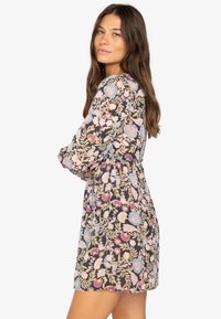 Blumenmusterkleid mit langen Ärmeln, tailliertem Schnitt und verspieltem Rock. Hat einen dunklen Grundton mit hellblauen, rosa und beigen Blumen.
