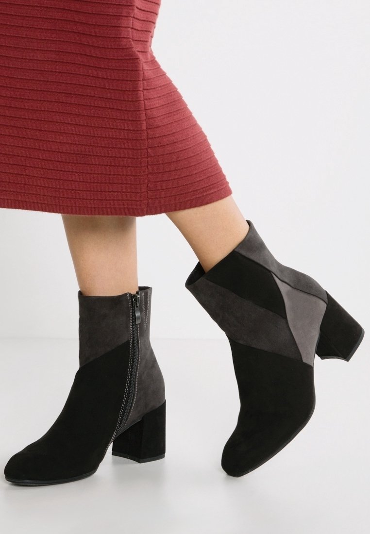Schwarze und graue Wildleder-Ankle Boots mit einem geometrischen Design, seitlichem Reißverschluss und einem stabilen Absatz, ausgestattet mit kontrastierenden Paneelen und einer glatten Textur.