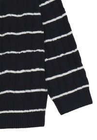 Il maglione a righe navy presenta righe orizzontali bianche, polsini a costine e un motivo a maglia testurizzato. La manica mostra una vestibilità rilassata.