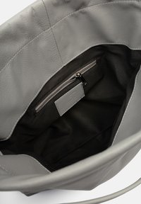 Sac fourre-tout en cuir gris avec une finition texturée. Dispose d'un intérieur noir, d'une poche zippée et d'une petite étiquette en relief.