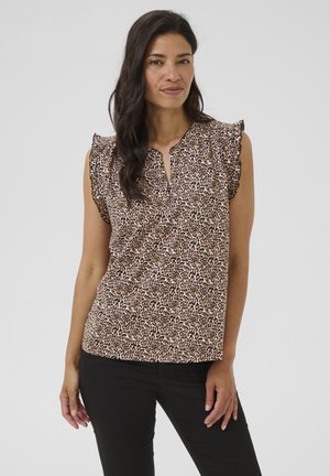 Blouse à imprimé léopard brun et crème, avec des manches courtes froncées, un décolleté en trou de serrure et une coupe ample. Associée à un pantalon noir.