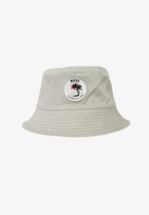 Cappello a secchiello beige chiaro con bordo cucito e toppa rotonda con due palme, tramonto e scritta "BOSS SUMMER OF 2000" sul davanti.