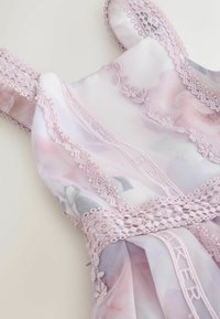 Vestido lila con tela floral transparente, tirantes de encaje intrincados y detalles bordados. Presenta un patrón floral y un acabado delicado.