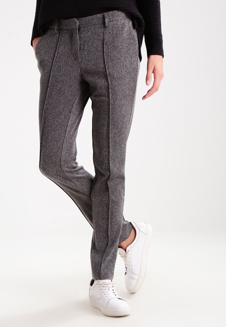 Pantalon gris en mélange de laine avec une coupe ajustée, doté de coutures frontales marquées et de poches latérales. Associé à des baskets blanches en cuir.