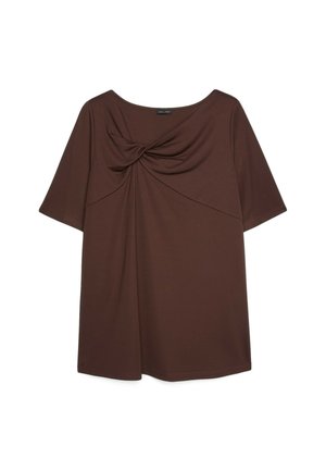 Bruine top met korte mouwen en een gedraaide knoopdetail op de borst en een ronde halslijn op een witte achtergrond.