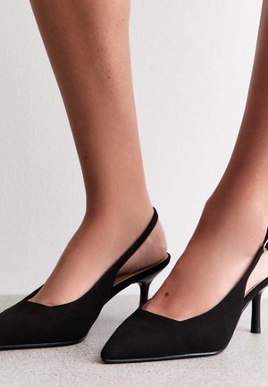 Tacchi slingback in suede nero con punta affusolata e tacco sottile. Presentano un piccolo dettaglio in oro sull'anello della caviglia.