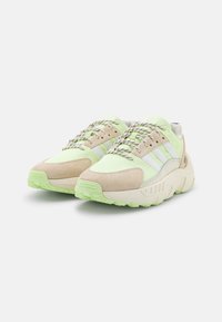 Leichte Sneakers mit einem Obermaterial aus Mesh in Mintgrün und Beige Wildlederakzenten, strukturierten Schnürsenkeln und einer kontrastierenden Gummisohle.