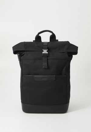 Zwarte roll-top rugzak gemaakt van duurzaam materiaal met een sluiting met riem, voorzien van een voorvak, leren accenten en een minimalistisch ontwerp.