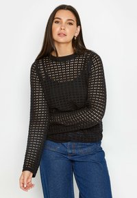 Maglione nero in maglia con design a rete aperta, maniche lunghe, scollatura a girocollo e vestibilità rilassata. Abbinato a jeans blu a vita alta.