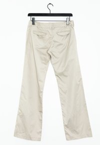 Beige weit geschnittene Hose aus glattem Material, mit Gesäßtaschen und flachem Bund, hängt an einem schwarzen Kleiderbügel vor einem weißen Hintergrund.