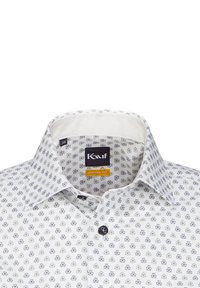 Camicia bianca con un dettagliato motivo floreale blu navy, design moderno, colletto a camicia e chiusura con bottone scuro.