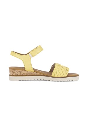 Sandale compensée jaune avec bride avant tressée, bride de cheville réglable, semelle intermédiaire en liège et semelle extérieure en caoutchouc blanc strié.