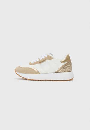 Baskets blanches et beiges avec lacets blancs, accents métalliques dorés, détail pailleté au talon et semelle blanche épaisse avec semelle en gomme.