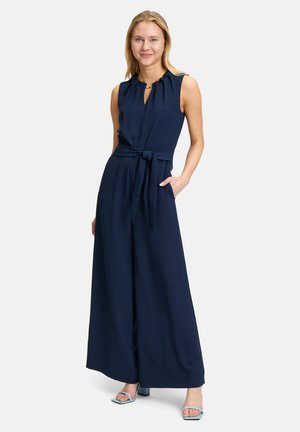 Combinaison sans manches bleu marine avec un bustier plissé, un décolleté en trou de serrure, une taille nouée et des pantalons à jambes larges ; comprend des poches latérales.