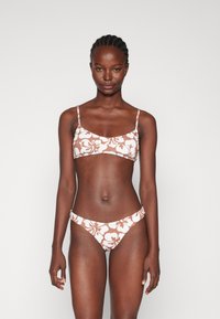 Barna és fehér virágmintás bikini szett, amelynek része egy cropped top vékony pántokkal és alacsony derekú alsó résszel, sima, rugalmas anyagból készült.