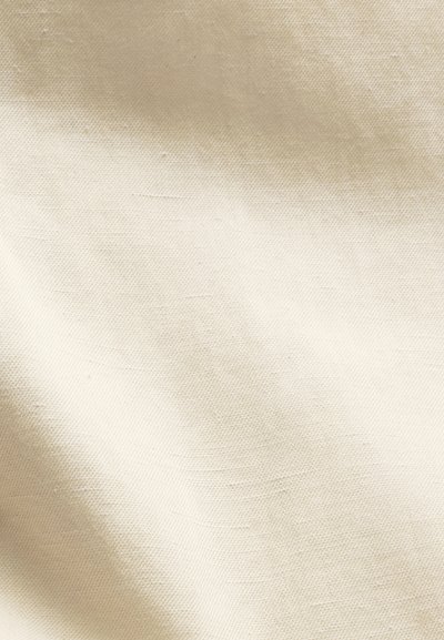 Gros plan d'un tissu texturé blanc cassé avec un tissage diagonal subtil et des ombres douces créant un effet de dégradé doux.