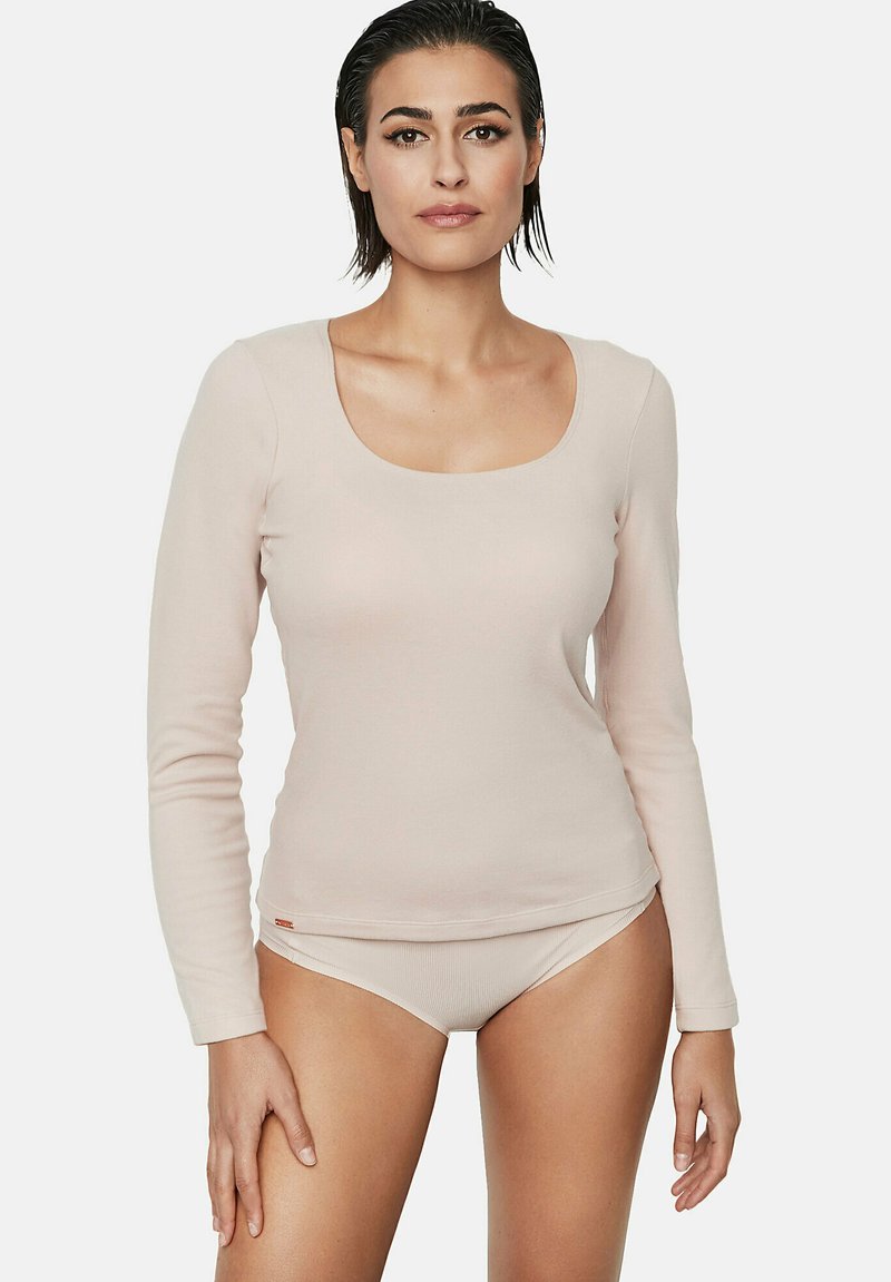 Haut à manches longues, de couleur rose pâle, avec un col arrondi et une texture lisse, associé à un sous-vêtement brief assorti dans une teinte similaire.