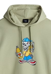 Groene hoodie met een grafisch ontwerp van een skelet karakter in een gele shirt, dat een drankje vasthoudt, met blauwe accenten en rode sneakers.