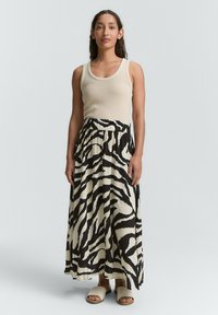 Beige Tanktop mit Rundhalsausschnitt, kombiniert mit einem langen, fließenden Rock im schwarz-weißen Zebra-Streifen-Muster. Glatter Stoff mit Gummibund.