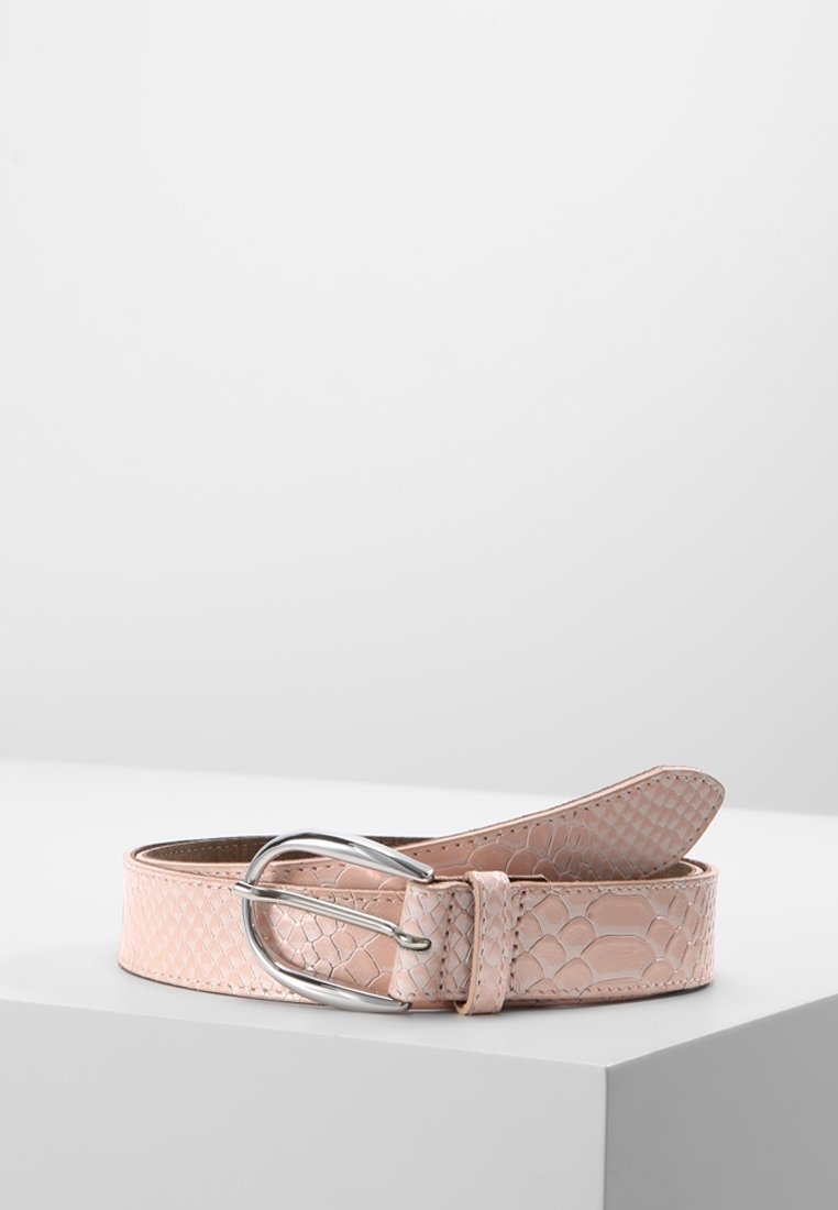 Ceinture en cuir texturé rose clair avec boucle ovale en argent, enroulée sur une surface blanche sur fond uni.