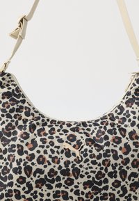 Sac imprimé léopard en beige, présentant des taches noires et brunes. Agrémenté d'un logo subtil et d'un matériau lisse et durable.