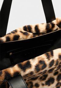 Zwarte totebag met een zachte binnenvoering van leopardprintbont, voorzien van een gouden rits en zwart leren accenten. Inclusief stevige dubbele handvatten.