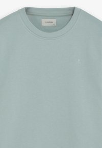 Lichtblauwe trui van zacht materiaal, met een ronde hals, geribbelde manchetten en een klein wit schedellogo op de linkerborst.